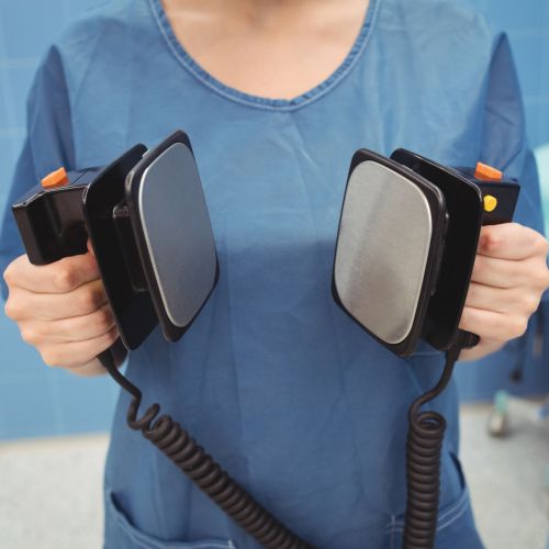 Mid section of female surgeon holding defibrillator at the hospital
