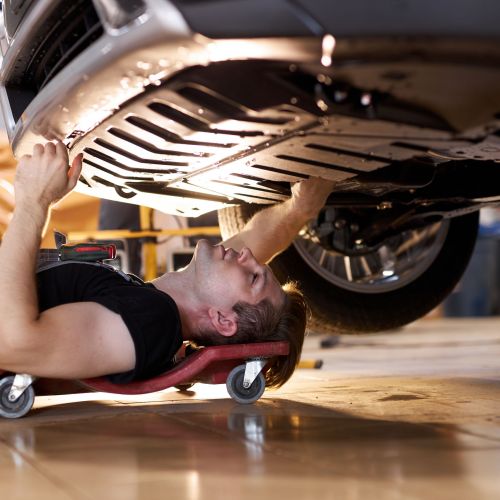 side view on concentrated auto mechanic male working alone on the floor