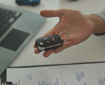 Young man receives a key from car salesman. After agreeing to a contract for rent or sale of a car at workshop, loan car, insurance, sale, buying car and finance concept.